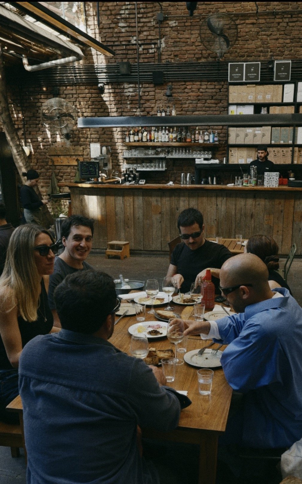 A group sharing plates and wine at a long table in a Buenos Aires restaurant